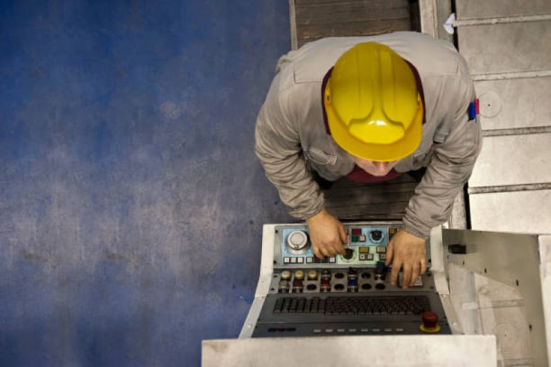 A worker is operating a machine in a factory for a leading building products manufacturer.