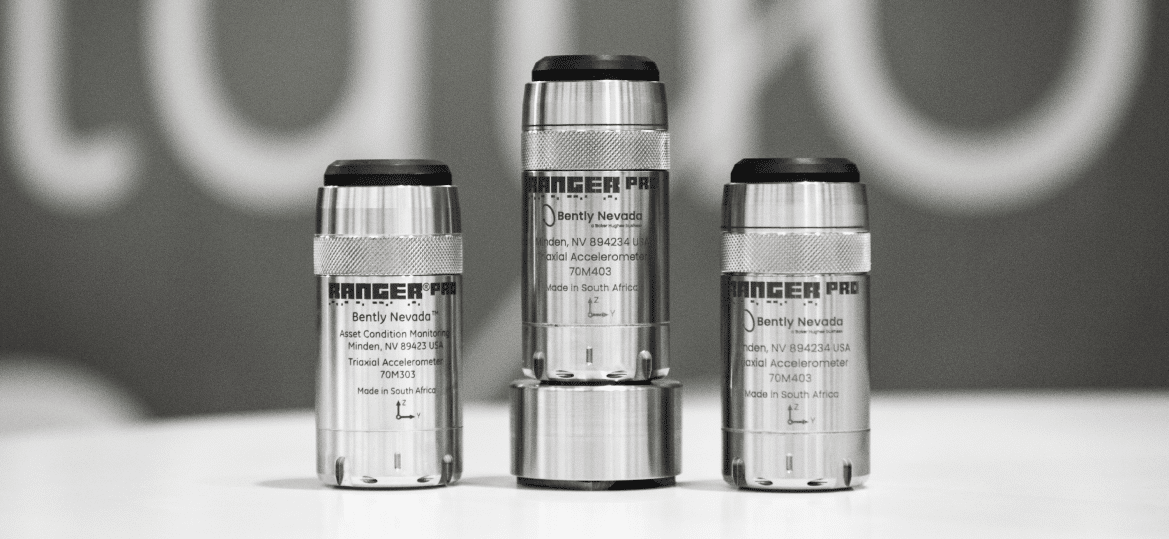 Three cylindrical Bently Nevada Ranger Pro accelerometers of varying heights are placed on a flat surface. They are metallic with text and specifications printed on their surfaces, showcasing their role in monitoring energy systems efficiently.