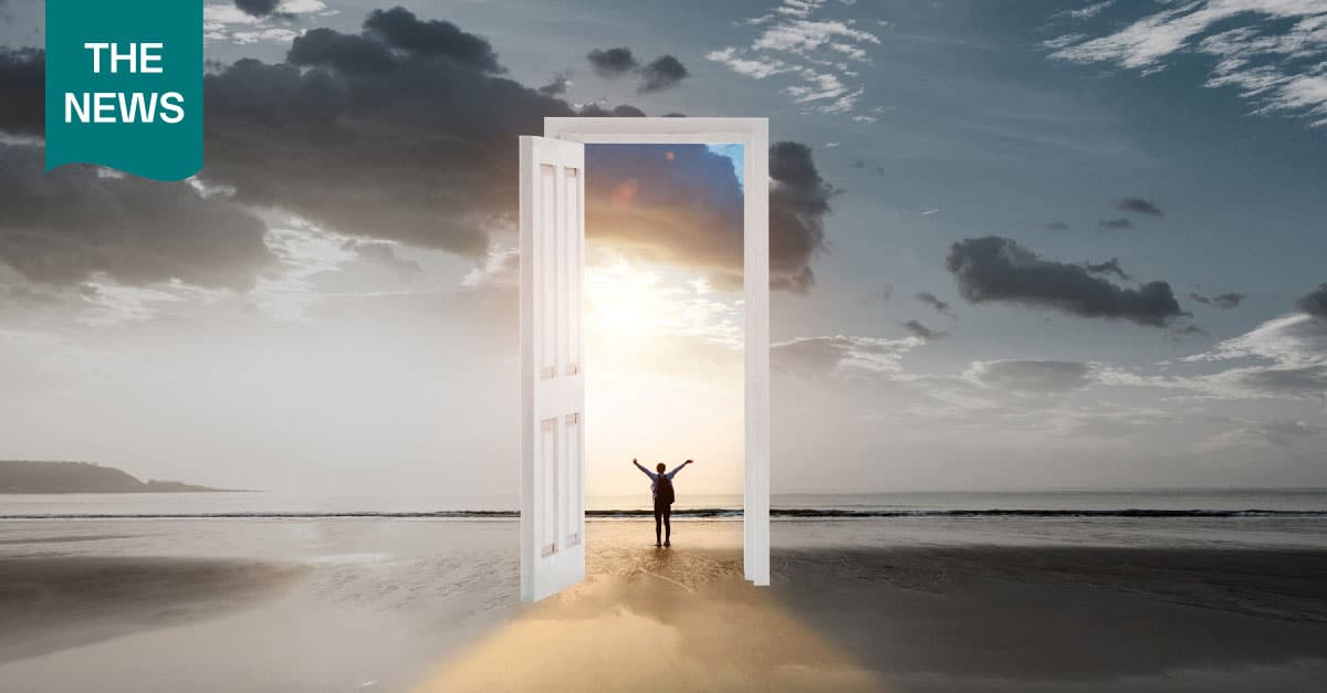 A figure on a beach is walking through a sun-infused door.