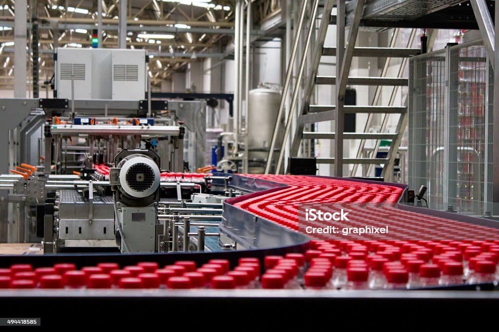 Red berry bottles on a conveyor belt in a factory stock photo.