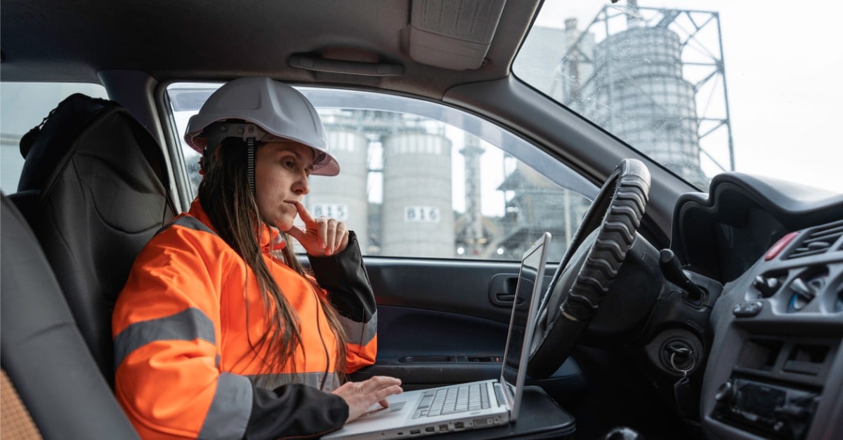 Picture of woman engineer in car looking at laptop and thinking.